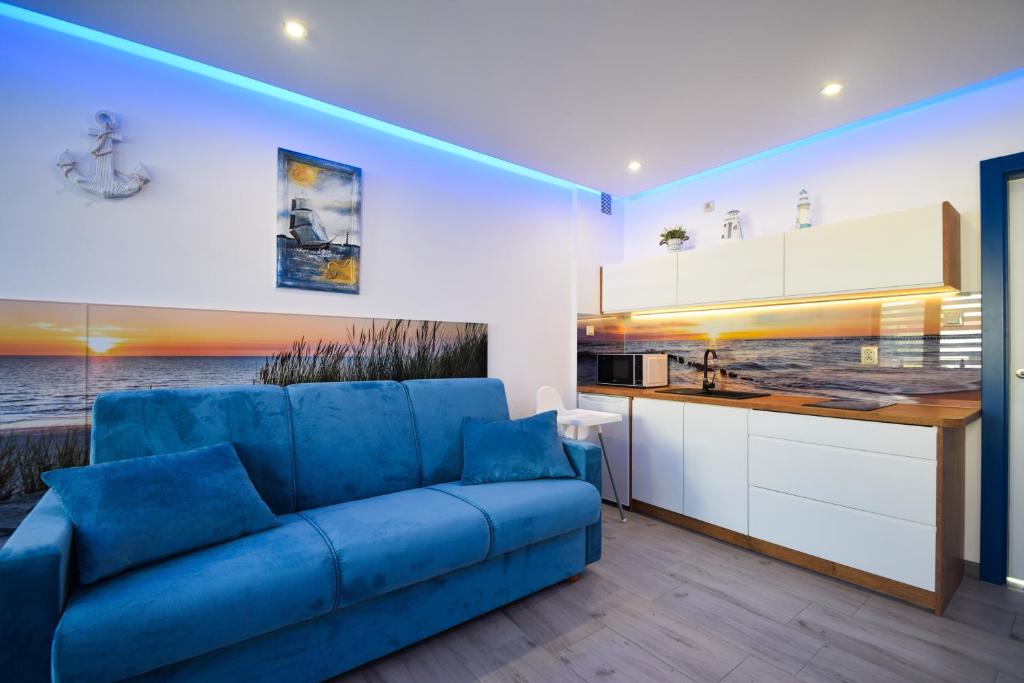 un soggiorno con divano blu e una cucina di Dafne1 apartamenty a Niechorze