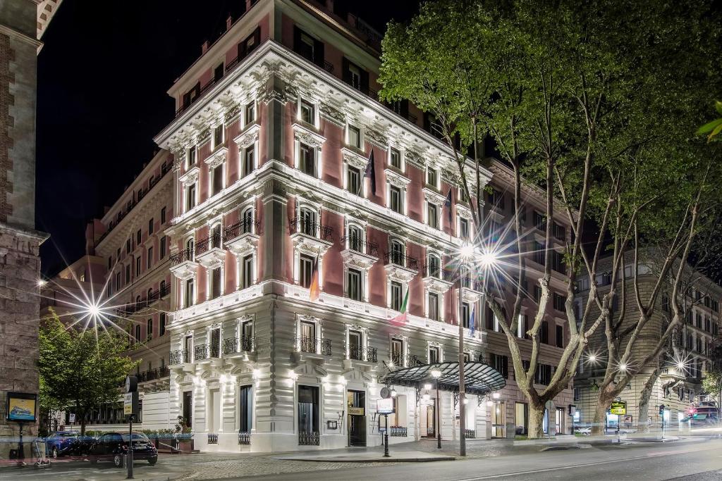 a tall building on a city street at night at Baglioni Hotel Regina - The Leading Hotels of the World in Rome