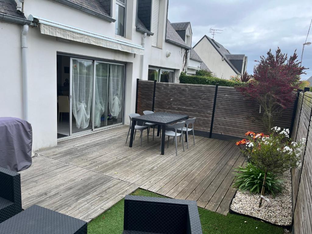 une terrasse en bois avec une table et des chaises. dans l'établissement Maison chaleureuse toute équipée pour vos vacances, à Saint-Quay-Portrieux