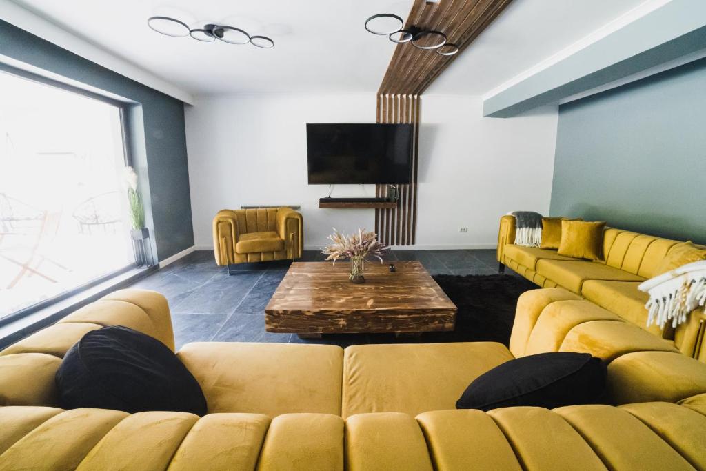 a living room with yellow couches and a tv at Voronet Noir Chalet in Voronet