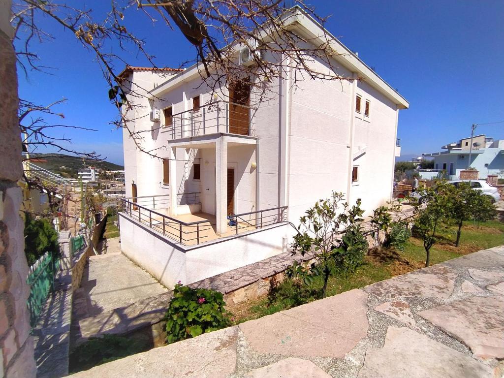 a white house with a balcony on a hill at Ahmeti Rooms in Ksamil