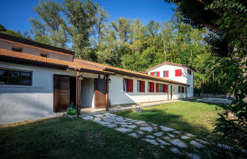 Casa blanca con ventanas rojas y patio en Agriturismo Ca' Poldo, en Ancona