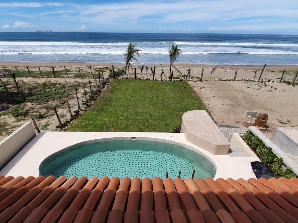 a swimming pool on the beach next to the ocean at New Beachfront Villa in Playa Blanca in Zihuatanejo