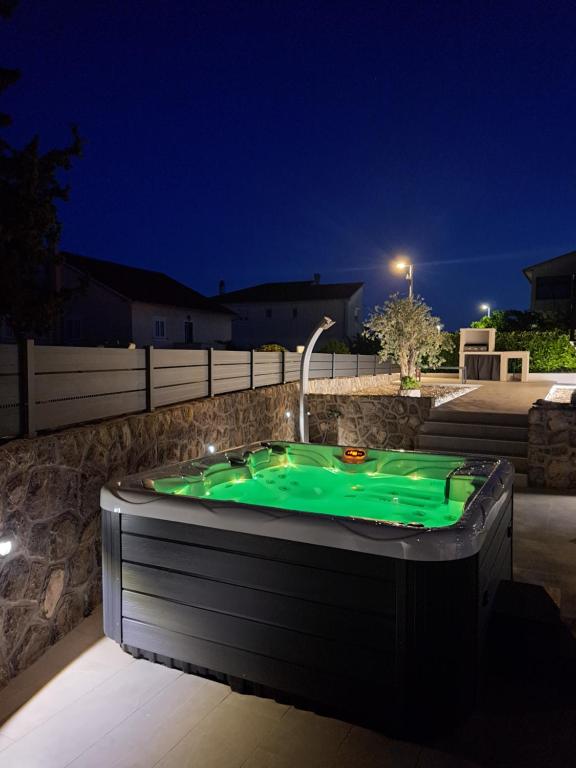 a hot tub with green water in a yard at night at Cosmopolitan Apartments in Krk