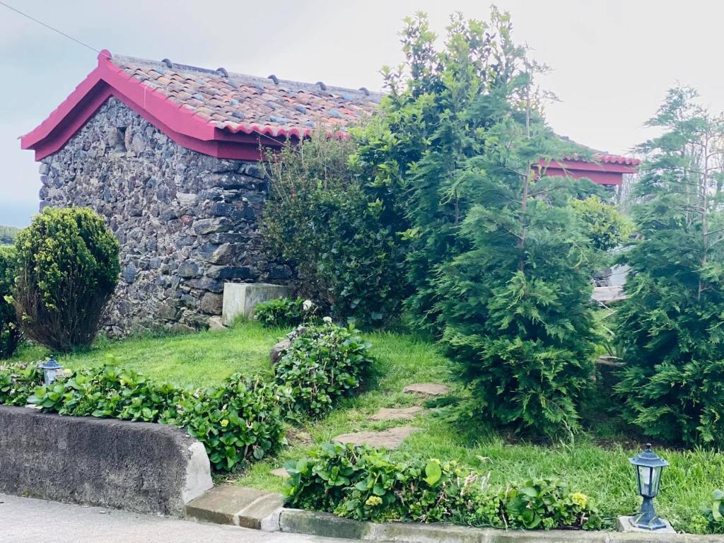 a stone house with a garden in front of it at Palheiro da Moenda in Lajes das Flores