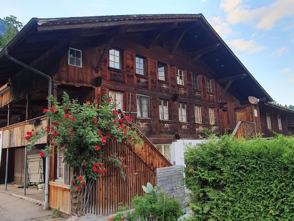 a large wooden building with red flowers on it at Haus Bergmann in Boltigen