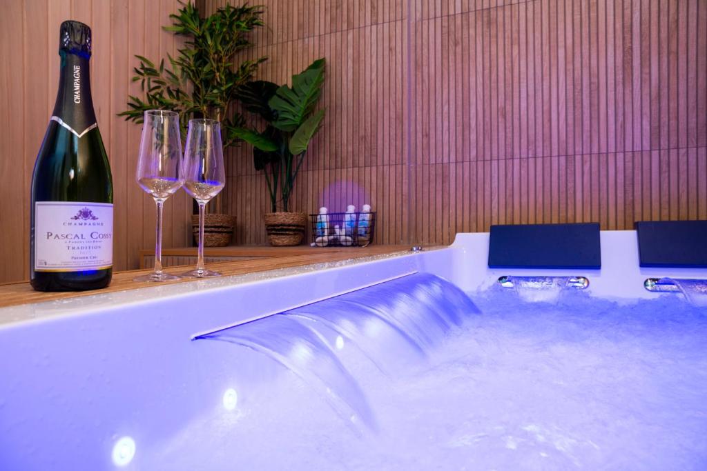 a bath tub with a bottle of wine and wine glasses at Art Déco Champagne & Spa in Reims