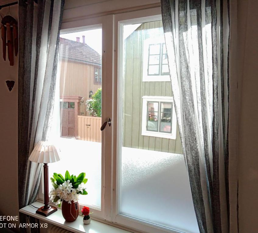 a window with curtains and a vase of flowers at Kalmarapartment in Kalmar