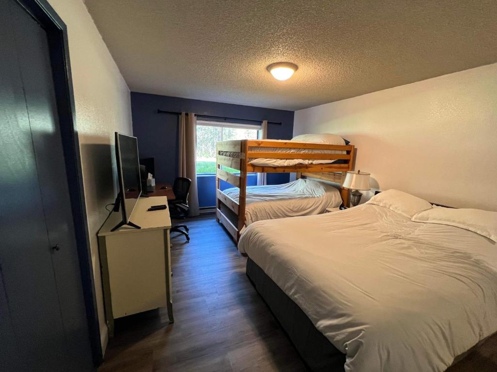 a bedroom with two bunk beds and a television at Rustic Girdwood Condo in Girdwood