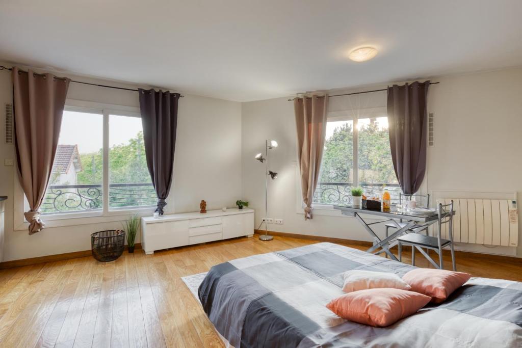 a bedroom with a bed and a desk and windows at Studio Moderne & Cosy Proche Paris in Rosny-sous-Bois