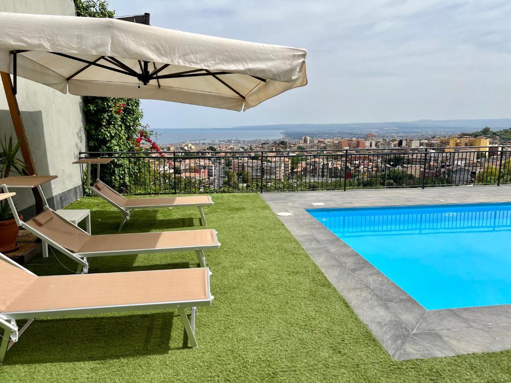 a pool with two lounge chairs and an umbrella at Villa Leucatia in Sant’Agata Li Battiati 