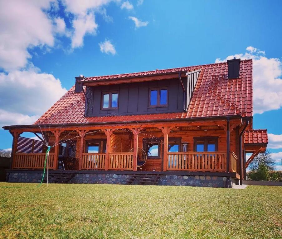 duży domek z czerwonym dachem w obiekcie Sielski Spokój Dom z bali Apartamenty całoroczne w mieście Gietrzwałd