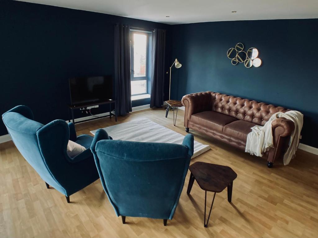 salon z brązową kanapą i niebieskimi krzesłami w obiekcie Joy St Apartments w mieście Belfast