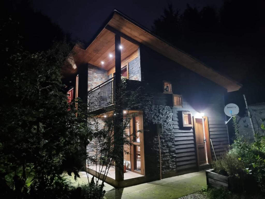 Casa iluminada por la noche con balcón en Relun Lodge en Villarrica