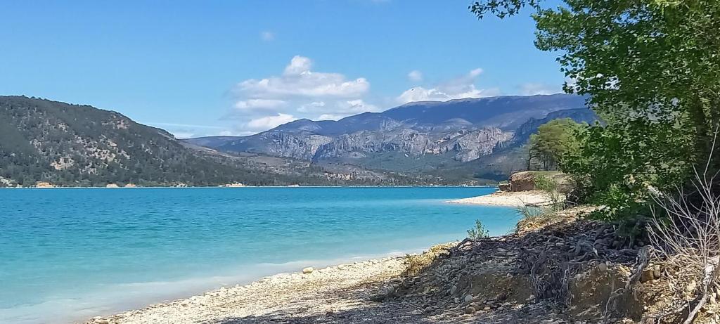 a view of a beach with mountains in the background at le studio du lac in Les Salles-sur-Verdon