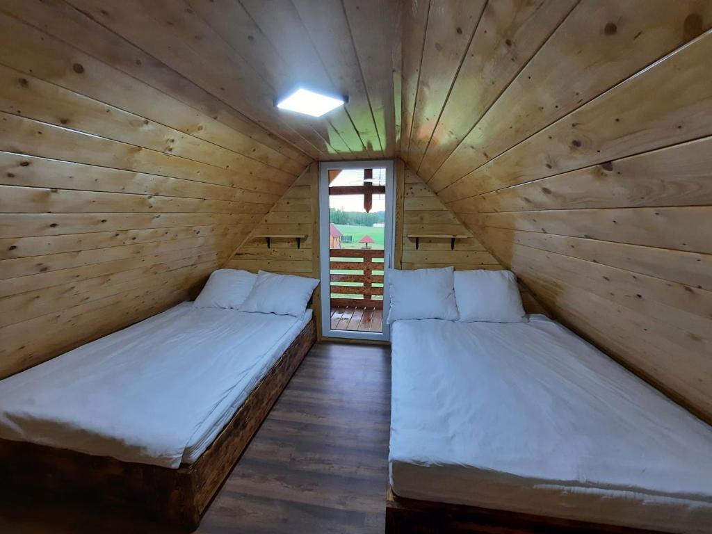 2 Betten in einem Holzzimmer mit Fenster in der Unterkunft Samosiejka - z widokiem na jezioro in Lidzbark