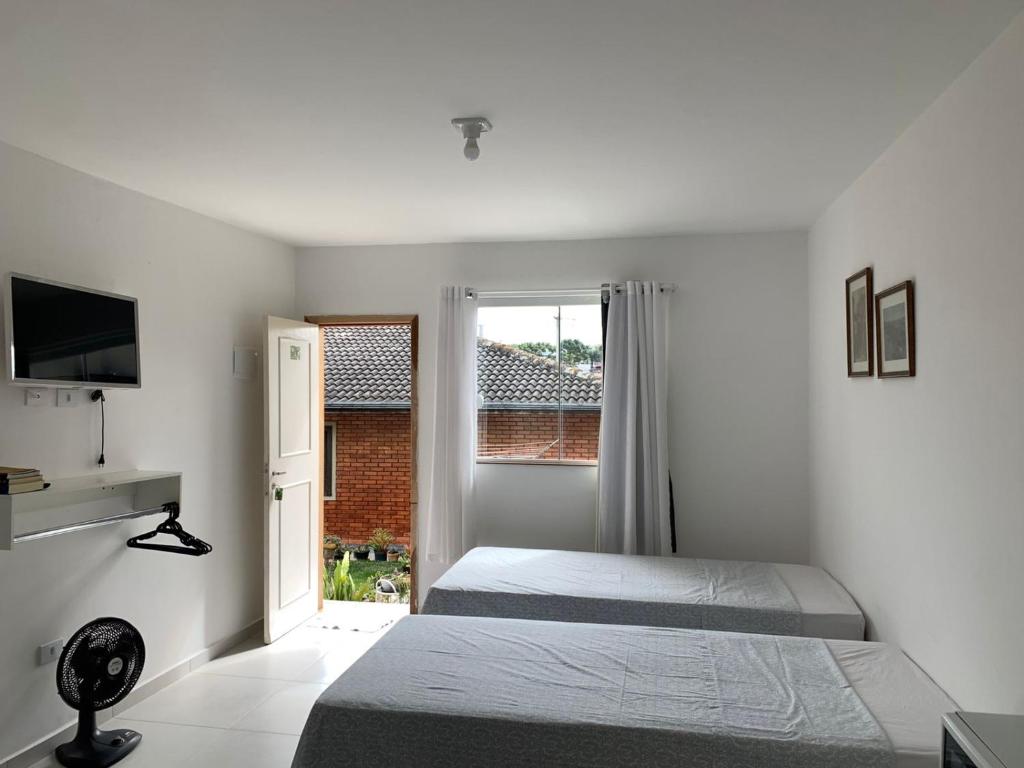 a bedroom with two beds and a window at STUDIO KITSOSSEGO in Curitiba