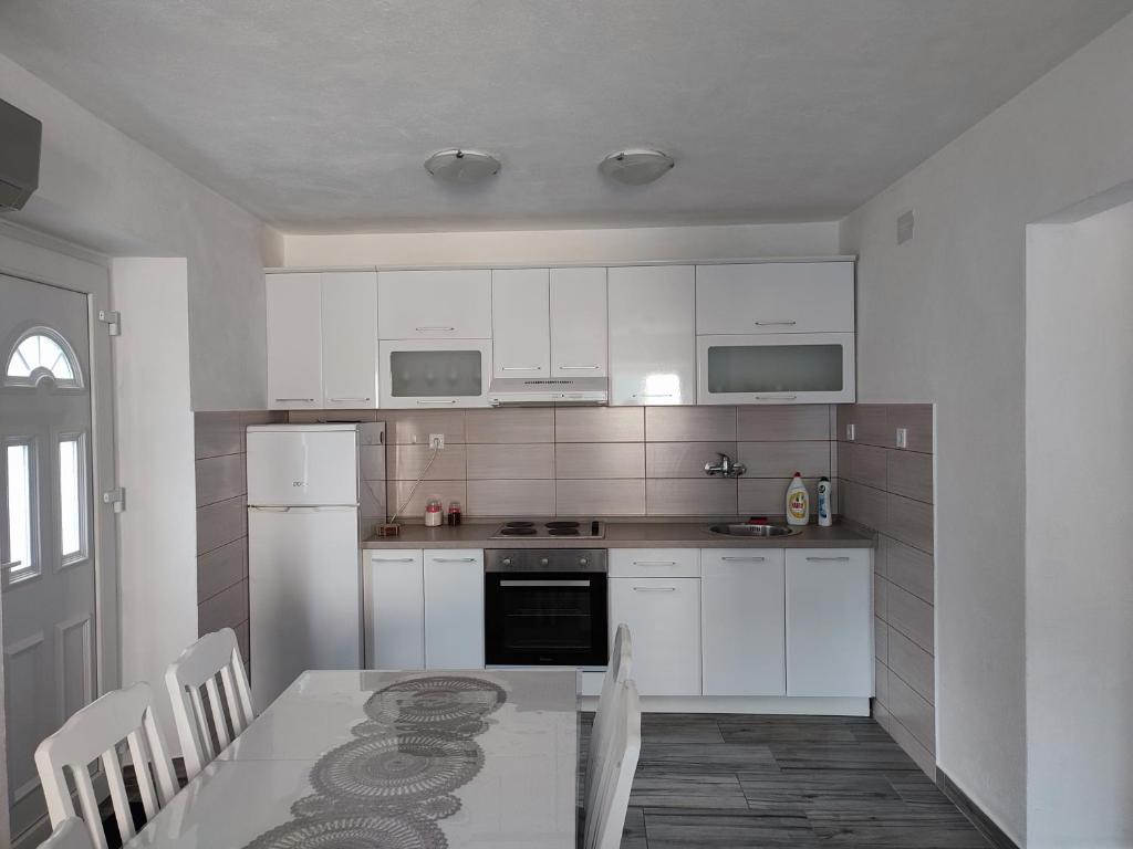 una cocina con electrodomésticos blancos y una mesa con sillas. en Apartment Rosić en Perast