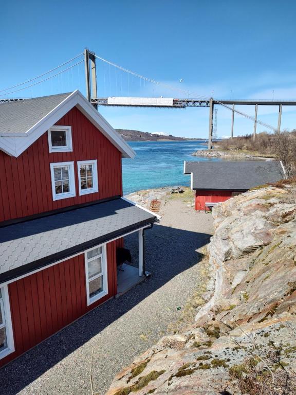 zwei rote Gebäude auf einem Hügel mit einer Brücke im Hintergrund in der Unterkunft Tjeldsundbrua Overnatting - Sjøhus1 in Evenskjer