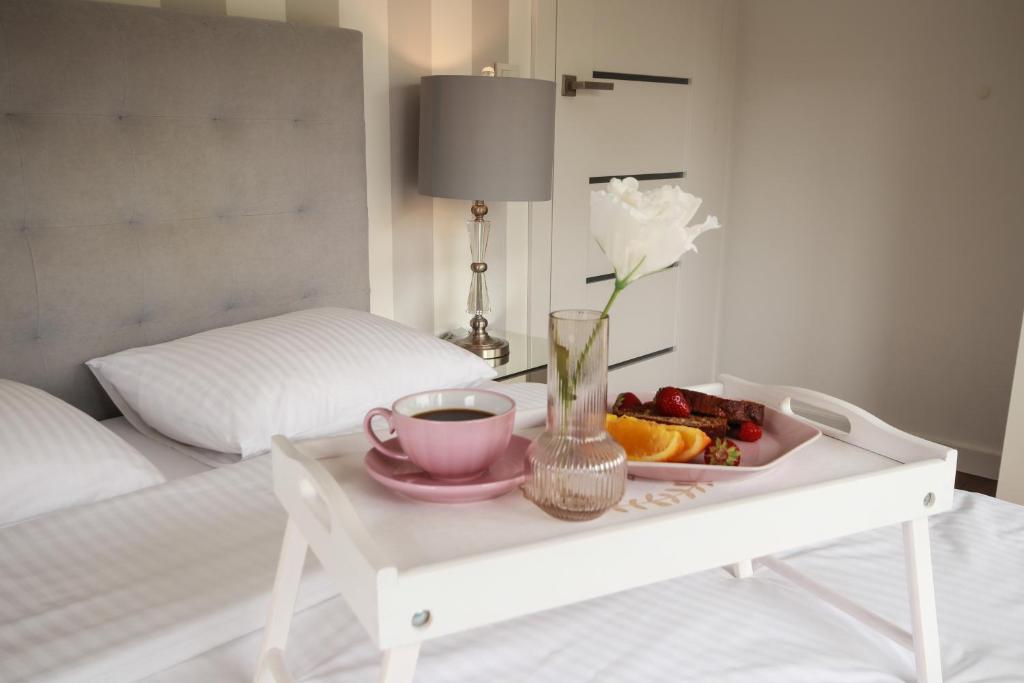 a tray of fruit and a cup of coffee on a bed at Apartament Rataje Park Poznań - Parking - Widok - 24h check in in Poznań