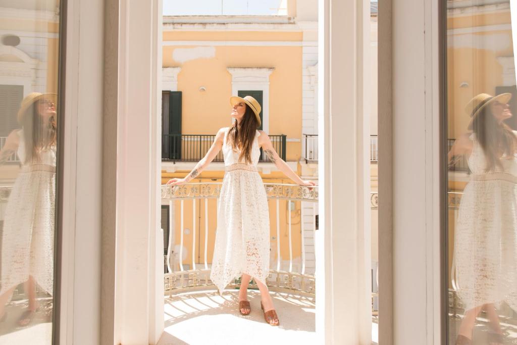 a woman in a white dress standing on a balcony at Le Dimore di Puglia - Palazzo Ladogana in Monopoli