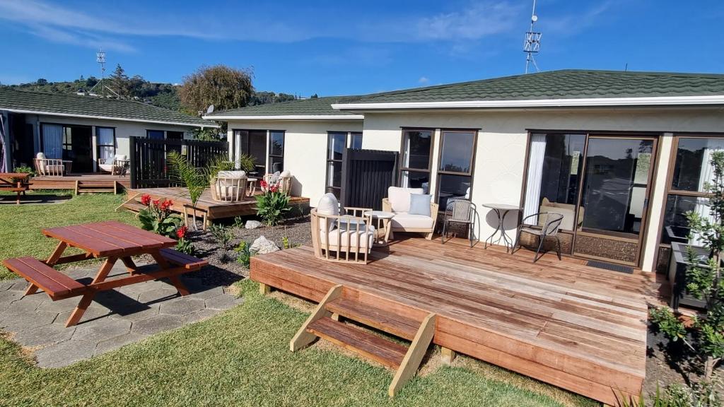 een achtertuin met een houten terras met een tafel en banken bij Tāhuna Beach Holiday Park in Nelson