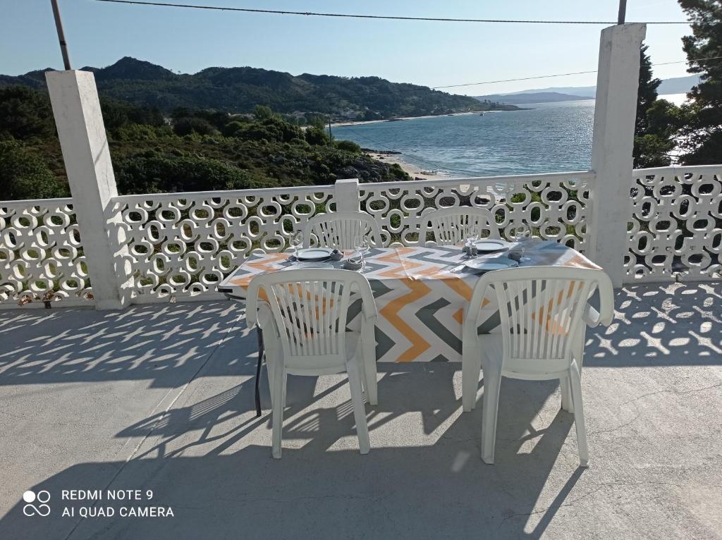 una mesa y sillas en un balcón con vistas al océano en Nuevo apartamento Montelouro en Louro