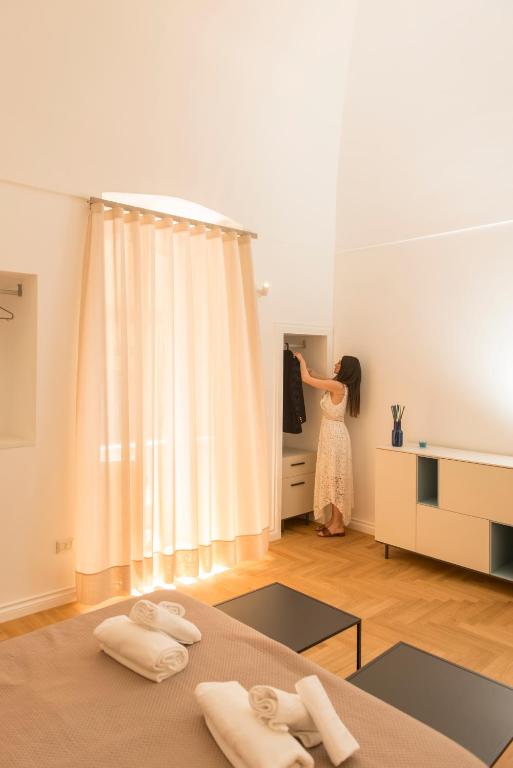a woman standing in a bedroom looking into a mirror at Le Dimore di Puglia - Palazzo Ladogana in Monopoli
