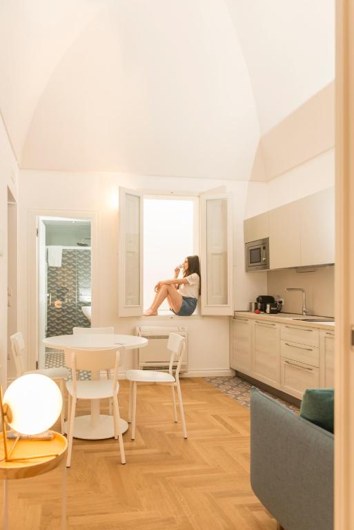 a woman sitting on a window sill in a kitchen at Le Dimore di Puglia - Palazzo Ladogana in Monopoli