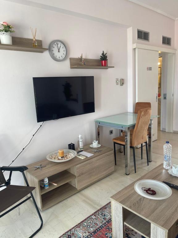 ein Wohnzimmer mit einem TV und einem Tisch in der Unterkunft Sunrise pearl in Attika Riviera apt and Parking in Rafina