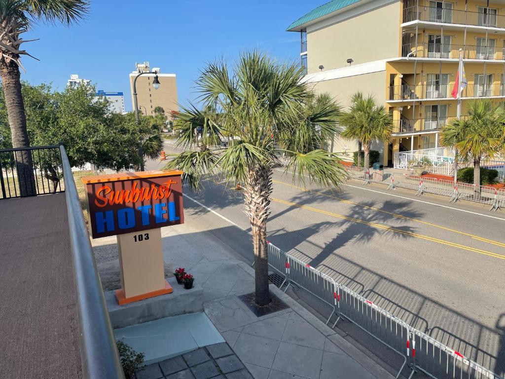 a hotel sign next to a palm tree on a street at Sunburst Hotel in Myrtle Beach