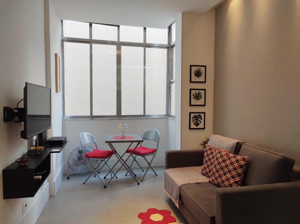 Hotel Charmoso Studio Leblon, a living room with a couch and a table with chairs at Charmoso Studio Leblon in Rio de Janeiro