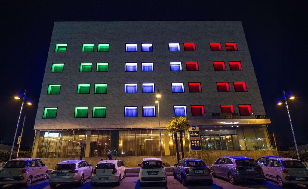 un bâtiment avec des voitures garées devant lui la nuit dans l'établissement Best Western Hotel Goldenmile Milan, à Trezzano sul Naviglio