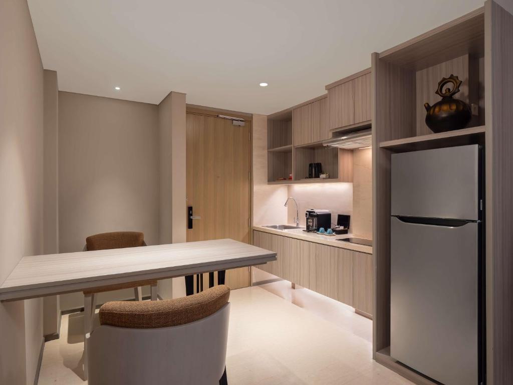 a kitchen with a table and chairs and a refrigerator at Radisson Lampung Kedaton in Bandar Lampung
