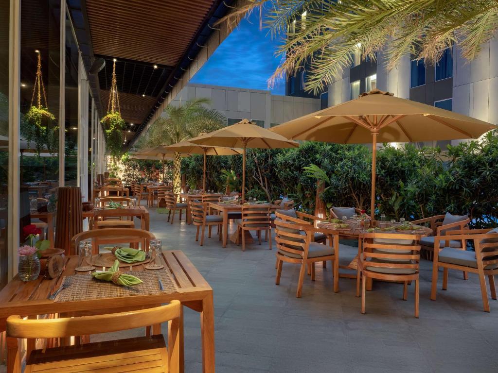 a restaurant with tables and chairs and umbrellas at Radisson Lampung Kedaton in Bandar Lampung