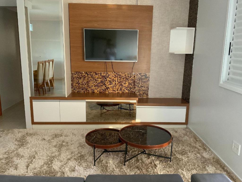 戈亞尼亞的住宿－Apt moderno 3 suítes churrasqueira Goiânia，客厅配有电视和桌子