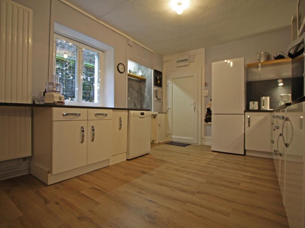 a large kitchen with white cabinets and a refrigerator at Gîte Plombières-les-Bains, 2 pièces, 2 personnes - FR-1-589-289 in Plombières-les-Bains