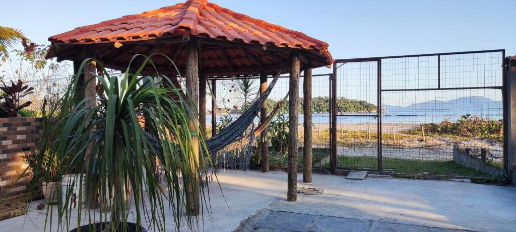 a gazebo with a hammock in front of the beach at Flat com portão na Praia in Angra dos Reis