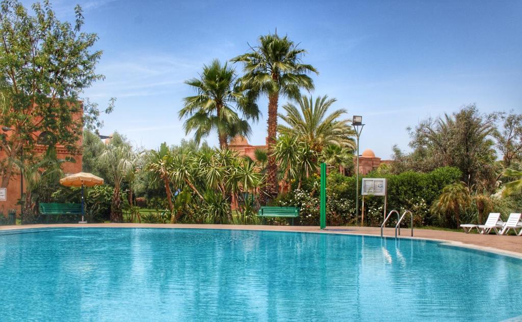 a large swimming pool in a resort with palm trees at Duplex Atlas Golf Resort Pοοl νieω Seriniτყ & Cαlm in Marrakesh