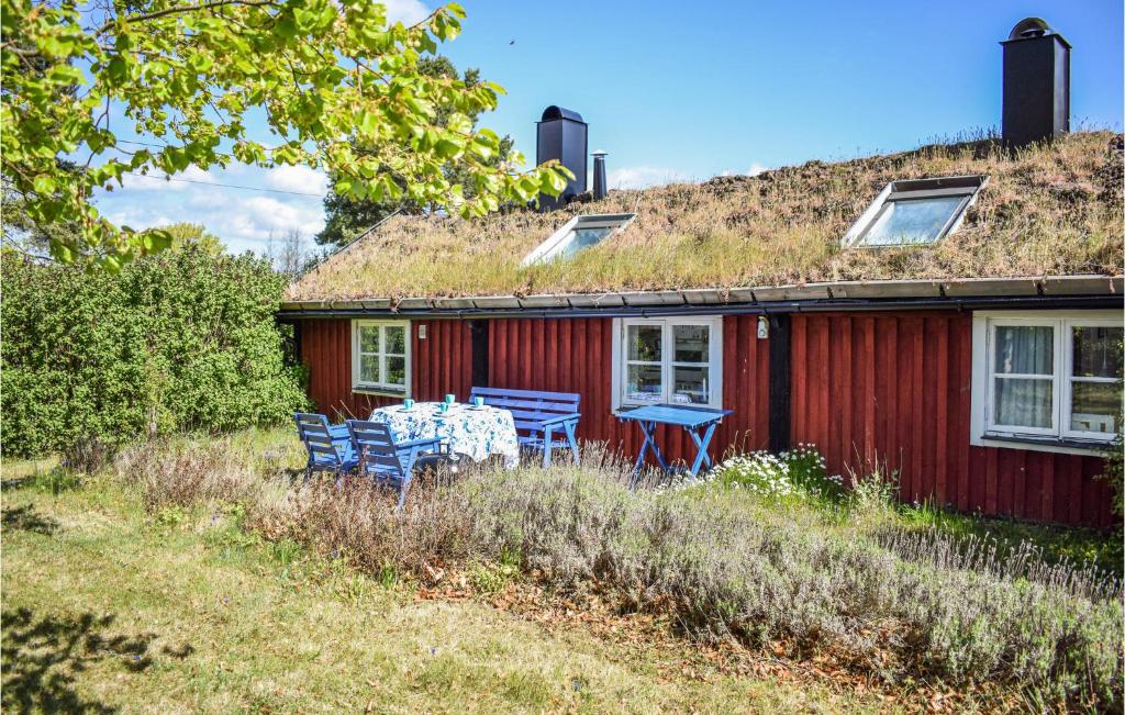 a red house with a grass roof with two blue chairs at 1 Bedroom Gorgeous Home In Kpingsvik in Köpingsvik