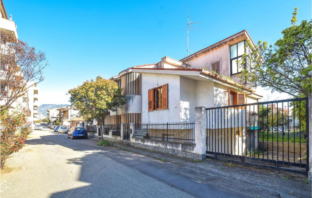 ein weißes Haus mit einem Zaun an einer Straße in der Unterkunft 3 Bedroom Gorgeous Home In Reggio Calabria in Reggio di Calabria
