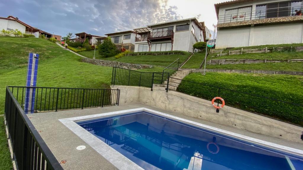 a swimming pool in front of a house at Apartamento con hermosa vista a 5 minutos del parque del café in Montenegro