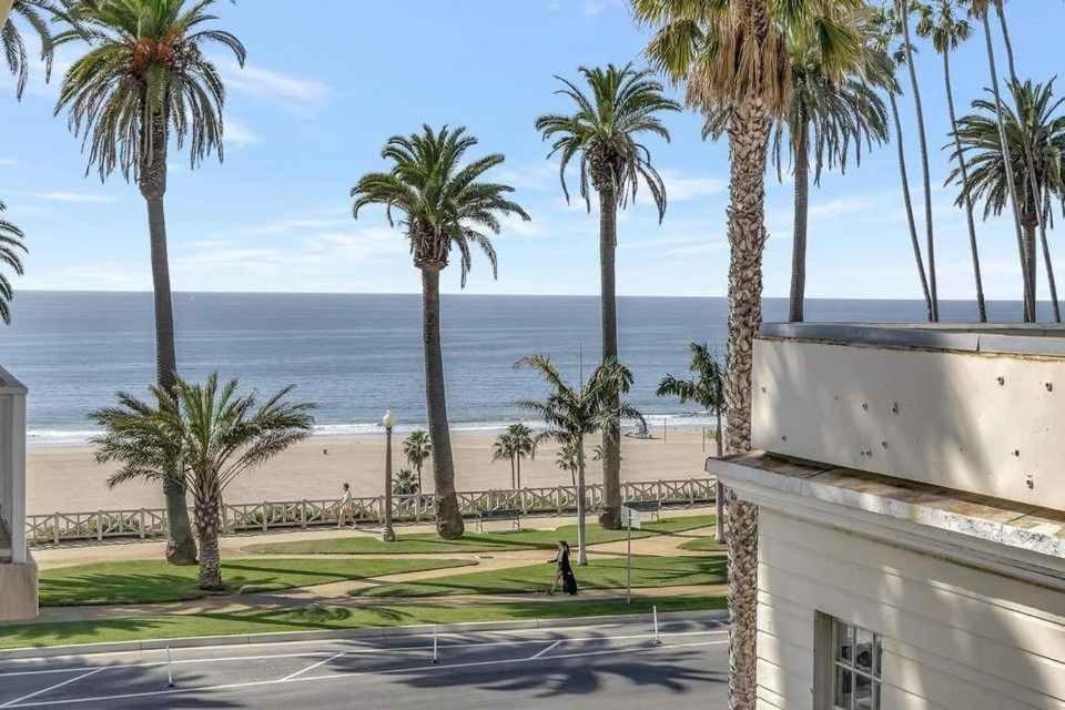 een uitzicht op het strand en palmbomen vanuit een gebouw bij 1 Luxury Apartment in Los Angeles