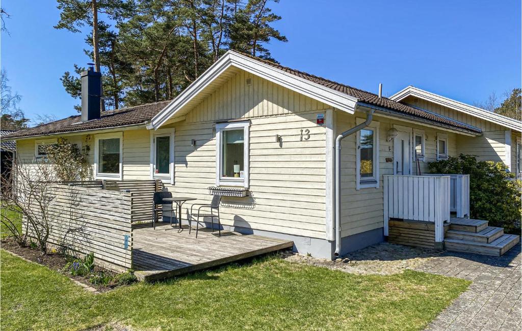 een klein wit huis met een houten veranda bij Beautiful Home In Skummeslvsstrand With Kitchen in Skummeslövsstrand