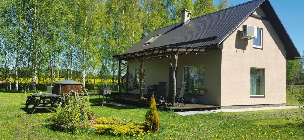 una pequeña casa con techo en un campo de césped en Burziņi, en Kuldīga