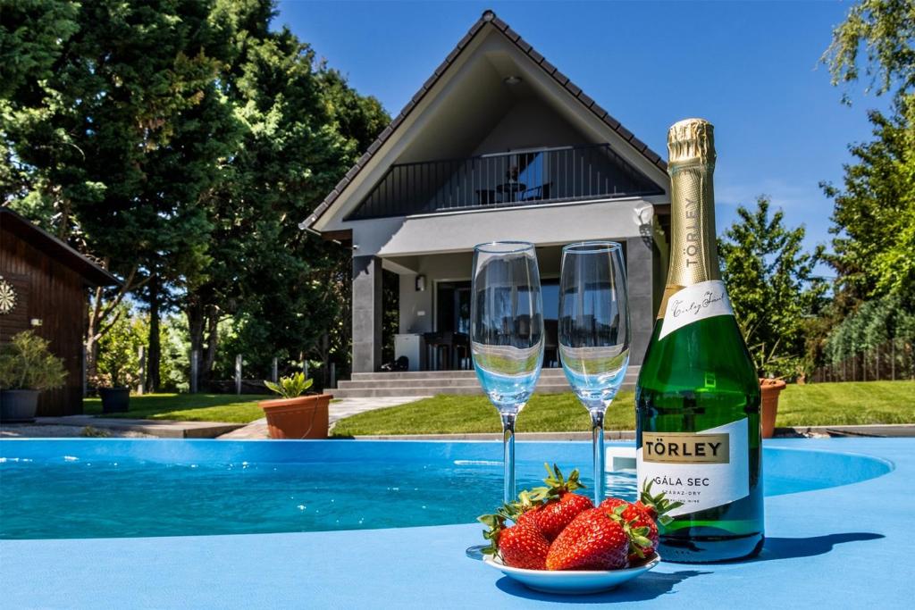 Una botella de champán y dos copas de fresas en una mesa. en Kővágó Vendégház Nagyfoki holtág en Szarvas