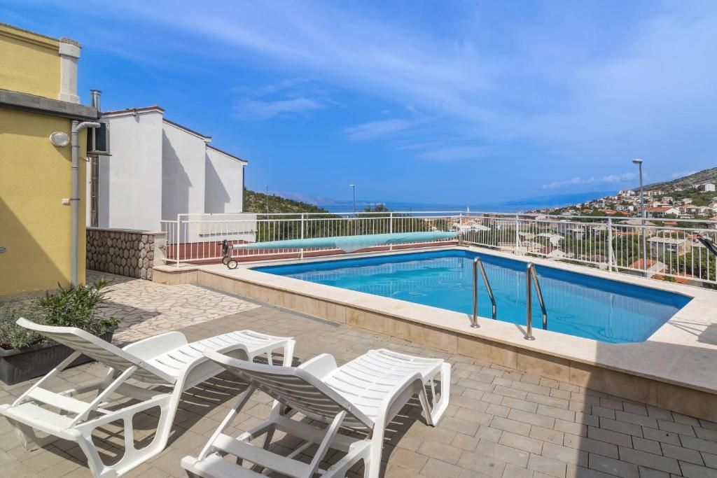 a swimming pool with white chairs next to a building at Apartments Zora in Senj