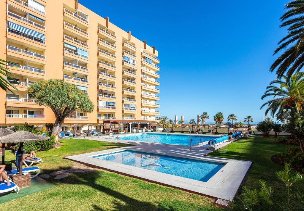 a resort with a swimming pool and a large building at Hotel Apartamentos Pyr Fuengirola in Fuengirola
