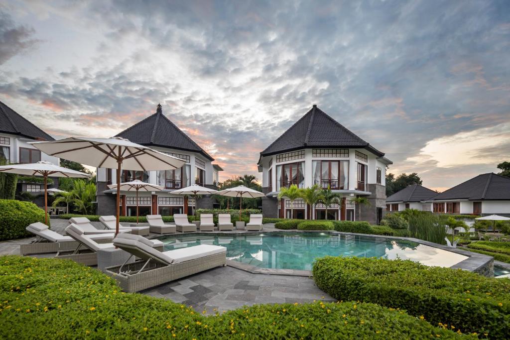 a villa with a swimming pool with chairs and umbrellas at Swan Paradise A Pramana Experience in Gianyar