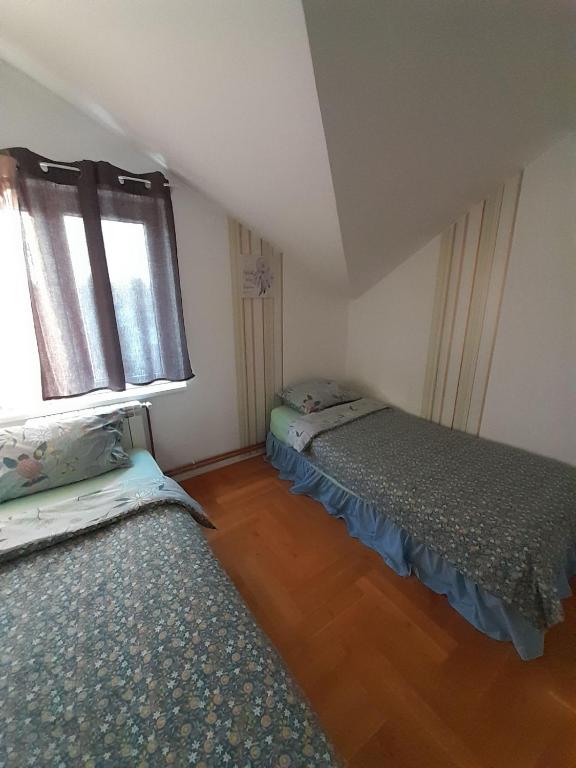 two beds in a small room with a window at Apartment Ken in Surčin